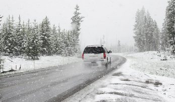 Imagen de un vehículo en una carretera mientras nieva